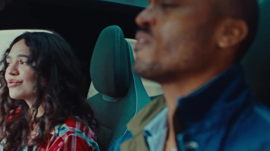 Man and a woman listen to music from her smartphone while driving on the highway during the daytime