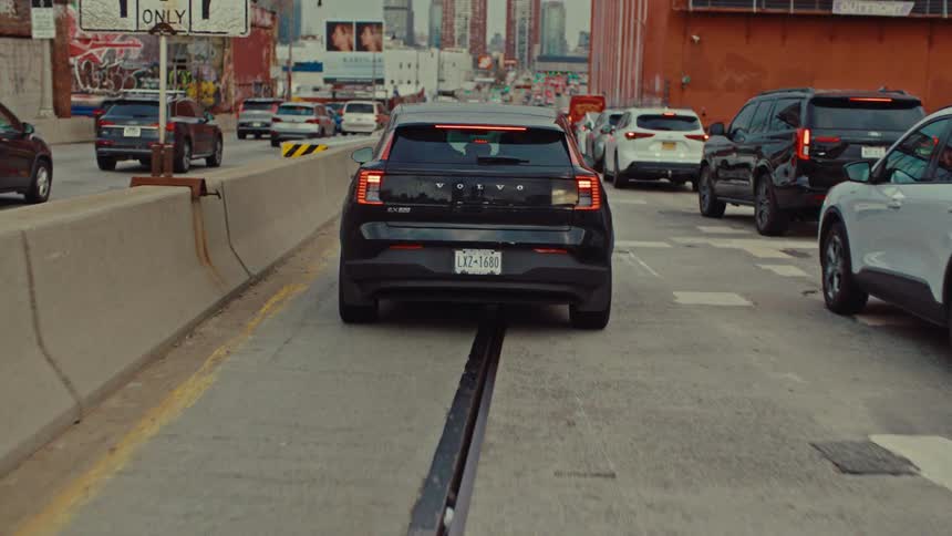 Black car on an urban road with heavy traffic between buildings