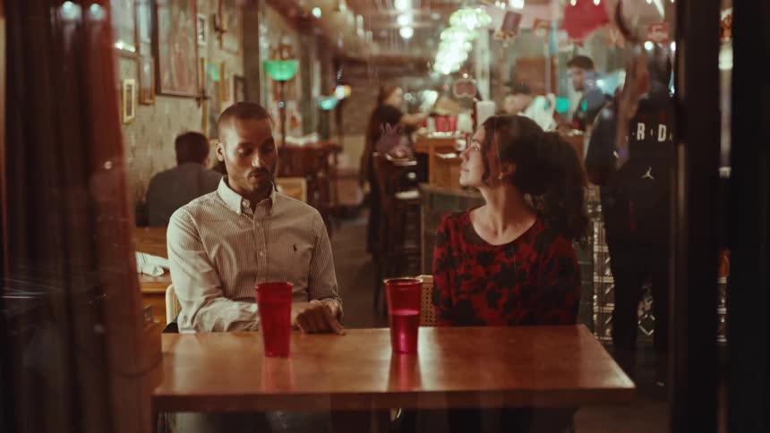 Man and woman sitting at a table with red cups in a restaurant