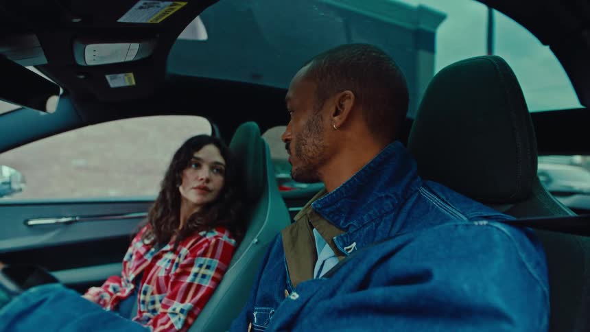 A man drives as he talks to a woman in the passenger seat