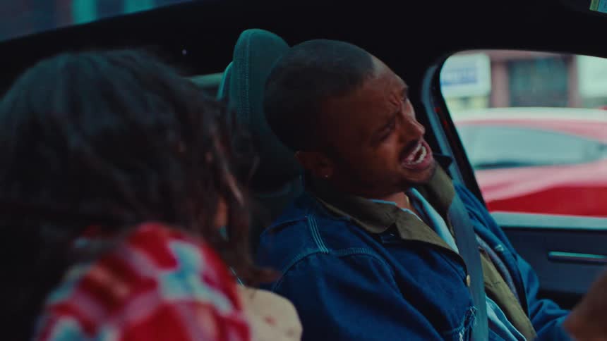 A man and woman driving in a car and singing