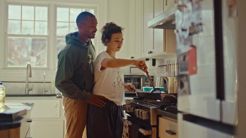 Couple smiles while cooking at home together during the daytime