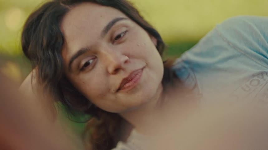 Woman lying on the grass with her head resting on her arm
