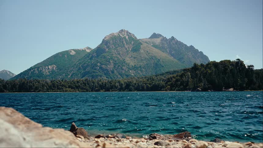 A group of mountains are located next to a rocky shoreline