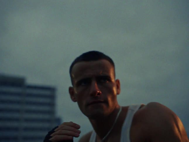 Young adult man wearing an undershirt shadowboxing on the rooftop of a building on a metropolitan area outdoors