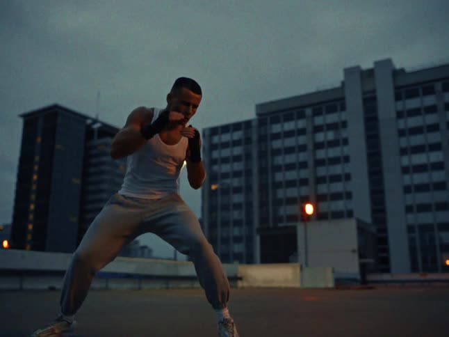 A man is shadow boxing outside in the city