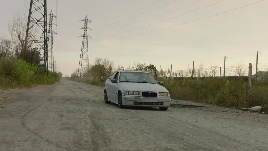 Two people in a car ride down a road next to power lines