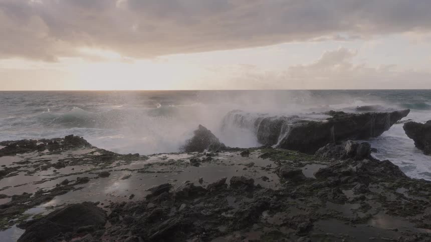 Waves splash against rocks along the coast as they roll in to shore