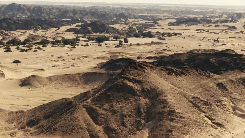 An aerial view of the desert with a mountain in it