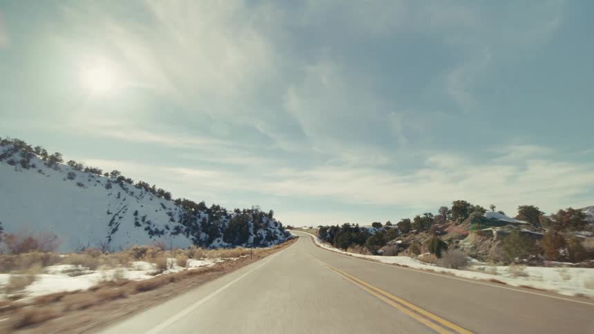Snow covering mountains and trees along a rural freeway