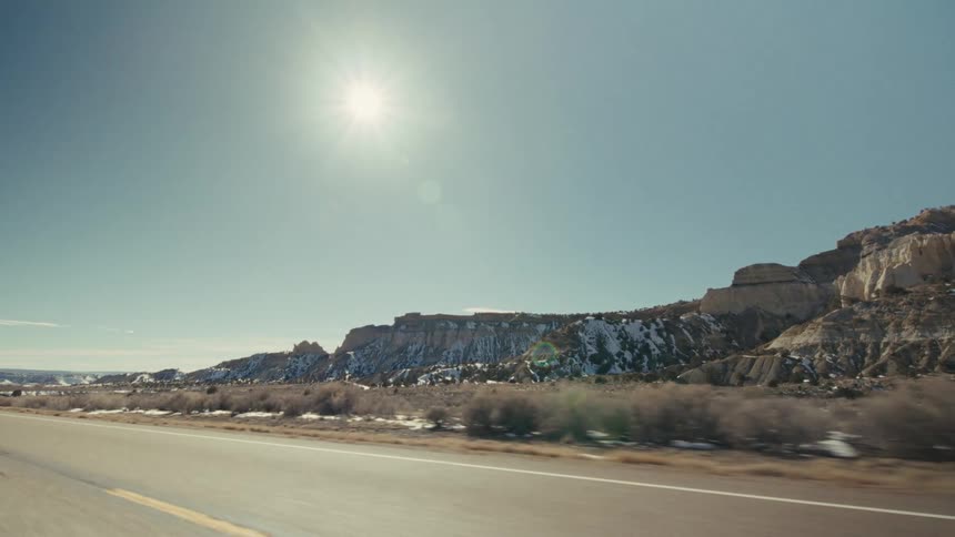 The sun flares high above the mountains