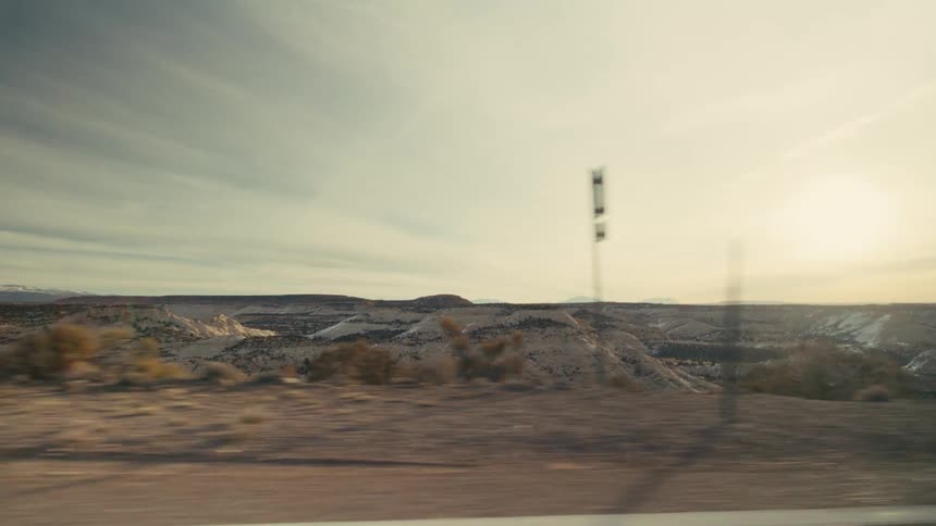 A vast desert landscape of rolling hills and plateaus under a bright sun