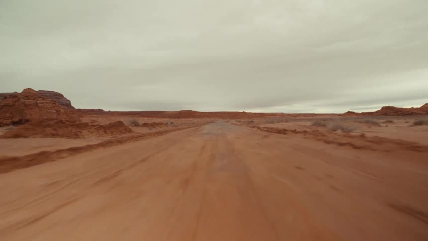 A remote road runs through a desert plain on a cloudy day