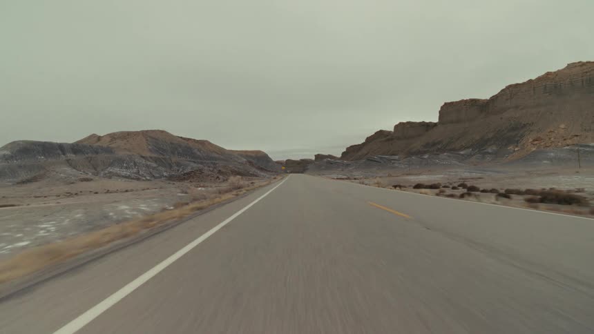 Traveling along a roadway that passes by a barren landscape