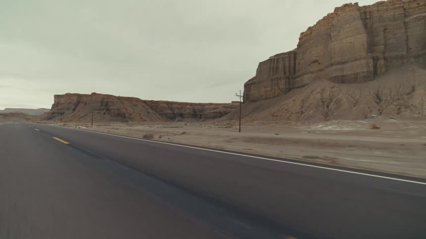 A road trip in the countryside along a road lined with canyons and hills at midday