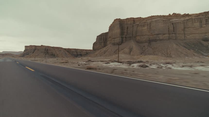 A road trip in the countryside along a road lined with canyons and hills at midday