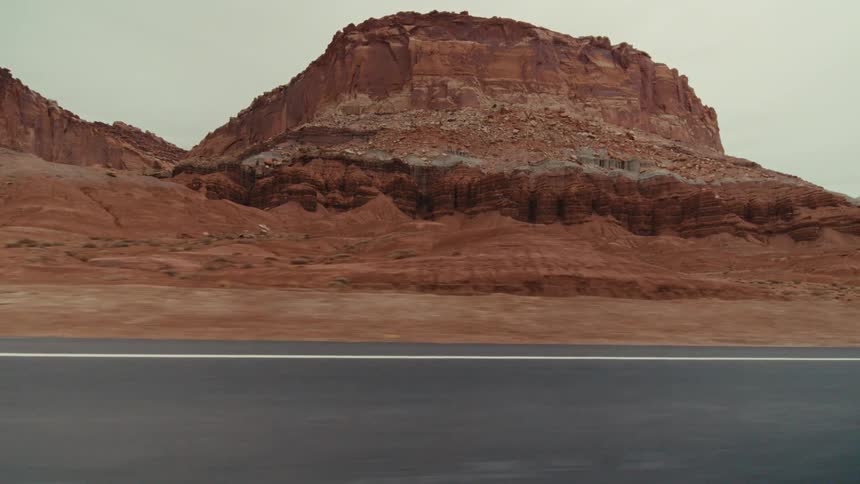 Traveling on a desert road through red rock mountains and canyons