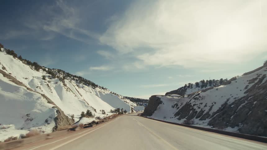 A freeway passing by a snowcovered mountain at midday in the countryside