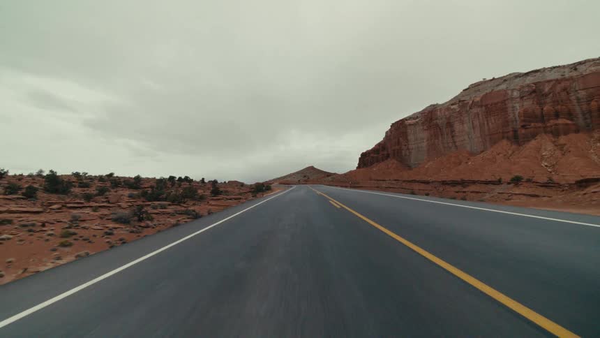 Traveling on a desert road through red rock mountains and canyons