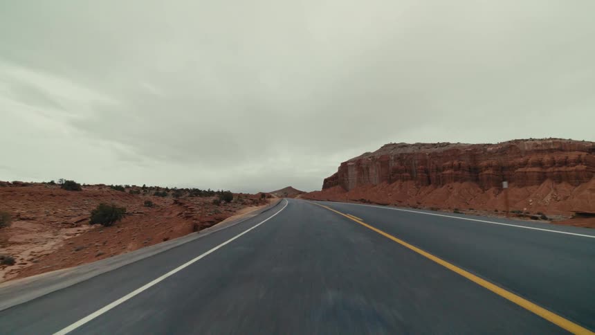 Traveling on a desert road through red rock mountains and canyons