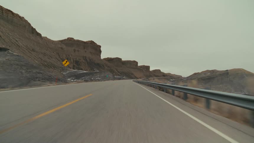 A road trip in the countryside at midday with a mountain range lining the roadside