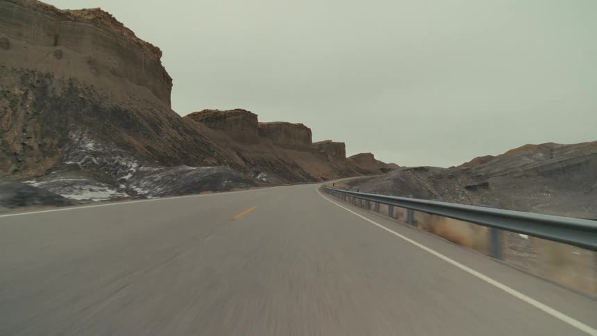 A road trip in the countryside at midday with a mountain range lining the roadside
