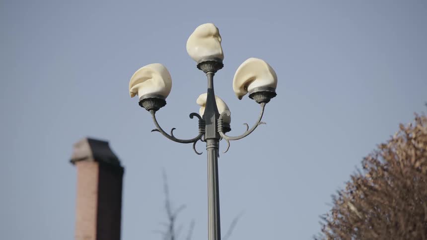 Metal light post with plastic globes that have melted in an urban area outdoors during day time