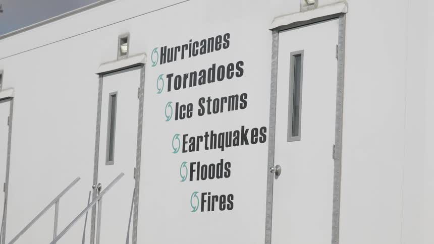 Exterior wall of a white building displays a list with hurricanes tornadoes ice storms earthquakes floods and fires next to two doors