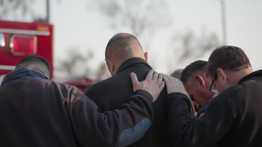 Back of people praying outdoor with hands placed on each others shoulders