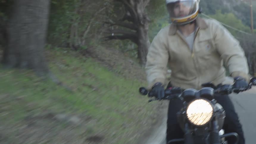 Young man riding a motorcycle on a rural road
