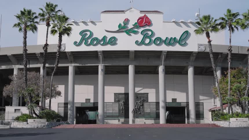 Palm trees stand near an entrance to the rose bowl on a summer day