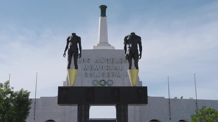 Two headless statues and a monument in front of the los angeles memorial coliseum