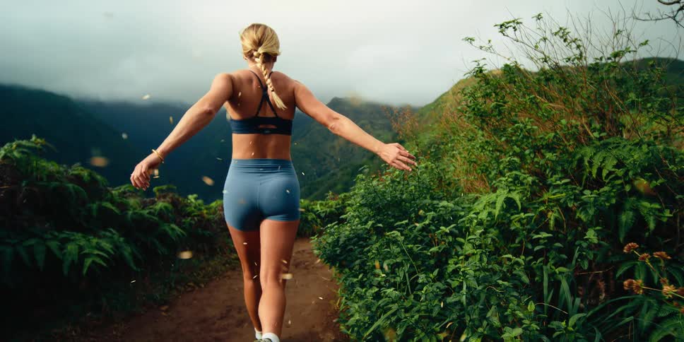 The woman runs on the trail at the mountain top