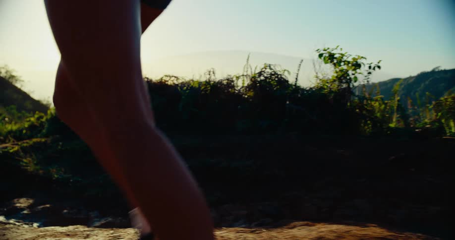 Woman steps on rocks as she runs on a mountain path