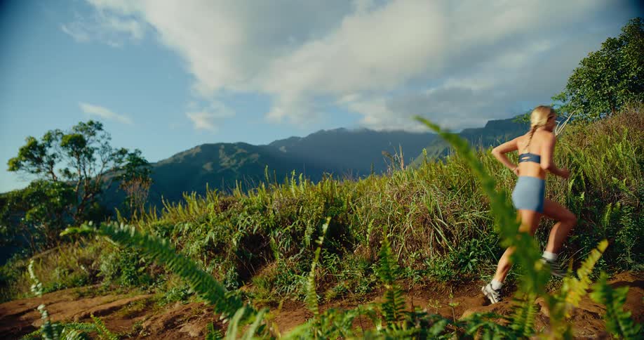 Sunlight shines on a woman jogging on a mountain trail