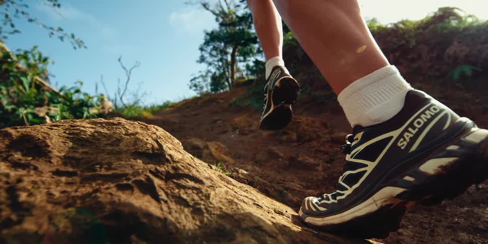 Slow motion of a woman running uphill along a dirt trail on a sunny day