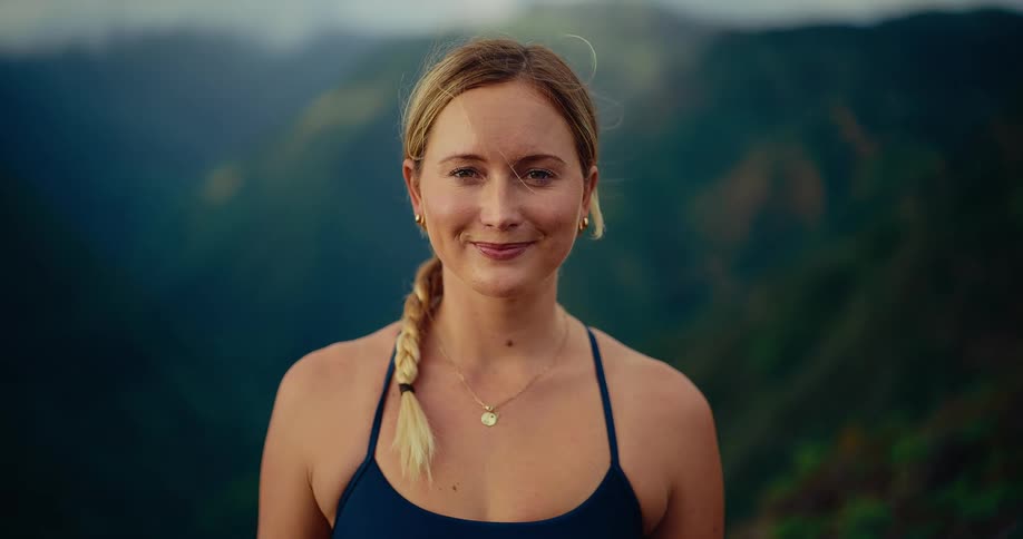 Woman stands smiling in the mountains as her hair moves in the breeze