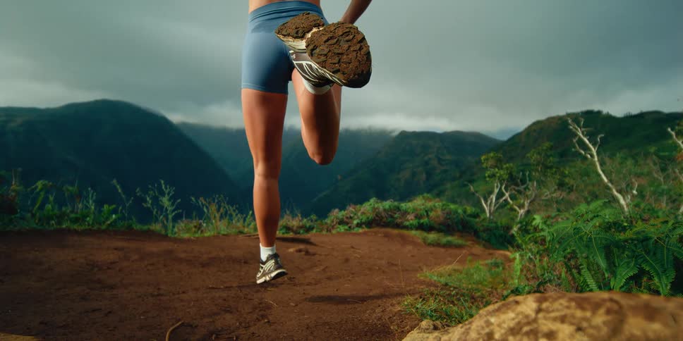 A woman is jogging on a dirt path in the mountains
