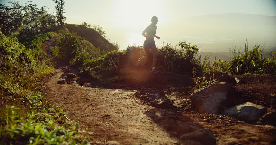 Woman runs along the edge of a mountain