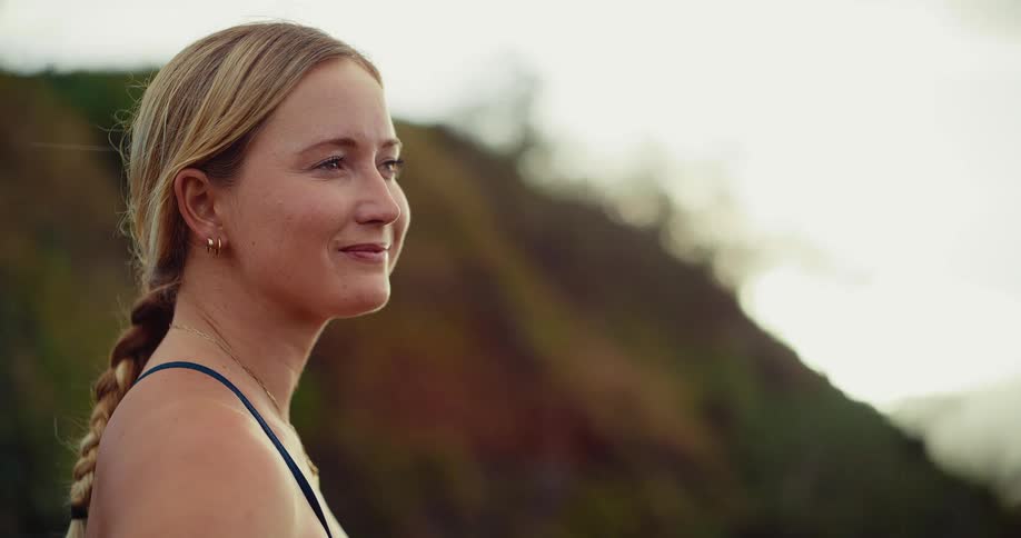 A woman is standing outside smiling in front of a mountain