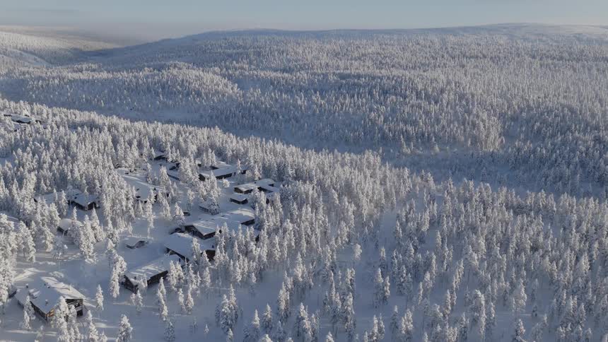 Frost covered forest surrounds a town in hilly terrain on a winter day