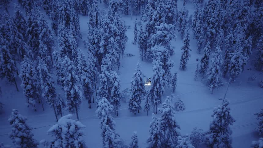 A person on a motorcycle in a snow covered forest