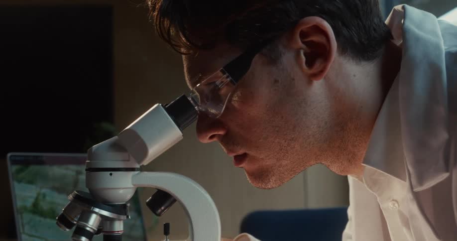 A man looking through a microscope in a lab