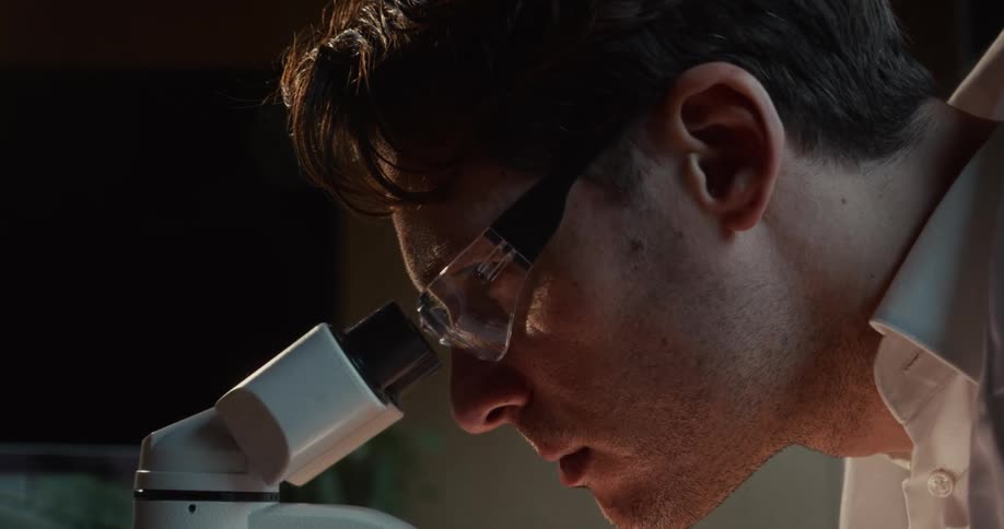 A man looking at items through a microscope