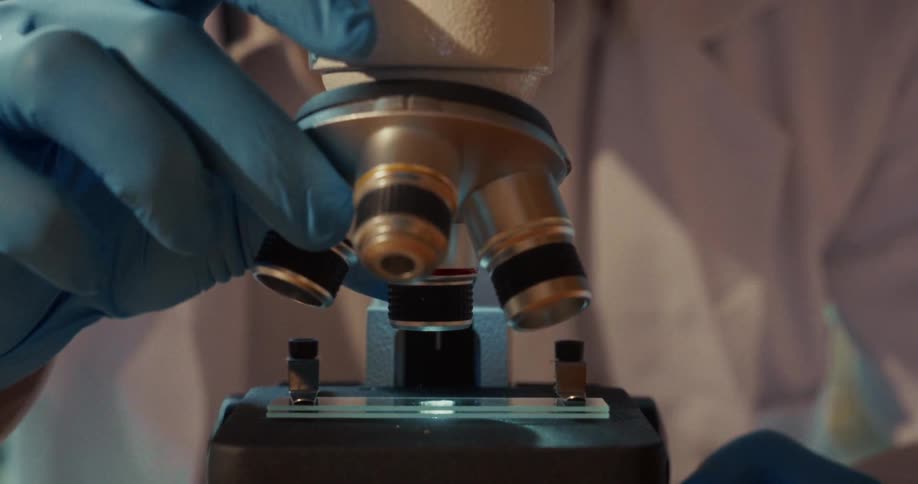 The man turns the lens on the microscope