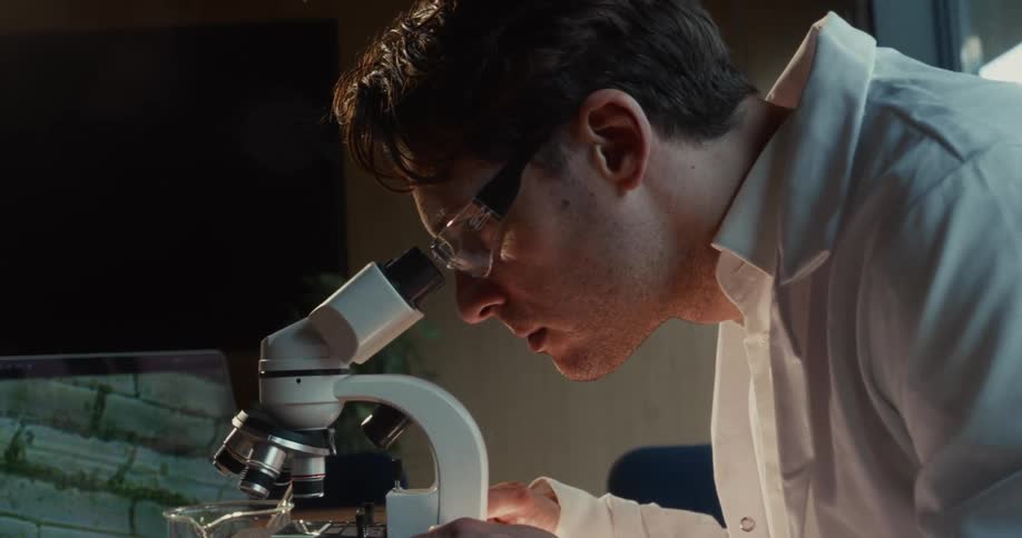 A man looking through a microscope in a lab
