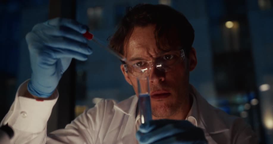 The scientist lifts the vial up in the lab