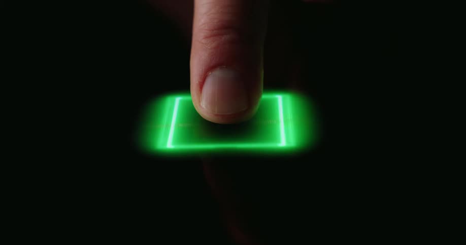 Videoa close view shows a person pressing a finger onto a dark surface as a green digital square glows and expands into a pattern of radiating green light beams
