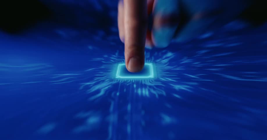 A person presses the index finger onto a glowing blue square button on a digital touchscreen triggering an illuminated animation of electronic circuit patterns that spread across the dark reflective surface in a futuristic display of technology