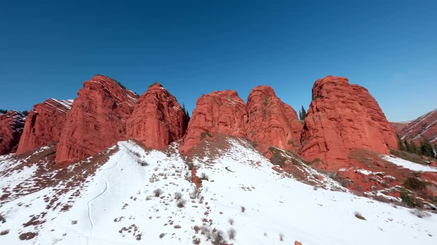 Red rock mountain canyons with snow covering the slope under a clear blue sky